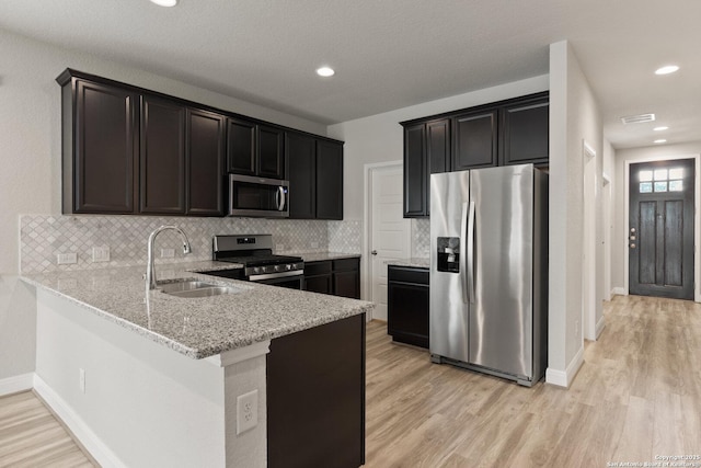 130 Abbeydell, Boerne, TX 78015 - kitchen featuring stainless steel appliances, a sink, light wood finished floors, backsplash, and light stone counters