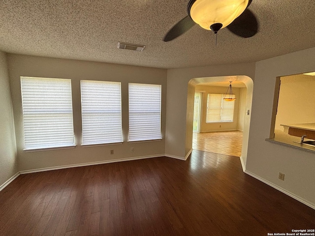 7835 Ruby Mdw, San Antonio, TX 78251 - spare room with arched walkways, wood finished floors, baseboards, a ceiling fan, and a textured ceiling