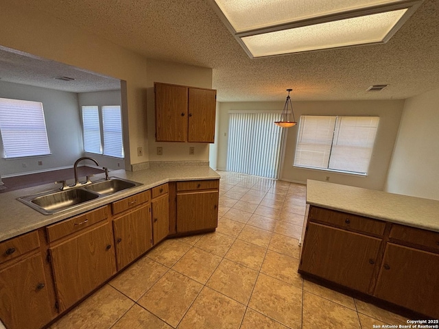 7835 Ruby Mdw, San Antonio, TX 78251 - kitchen featuring a sink, light countertops, a textured ceiling, light tile patterned floors, and hanging light fixtures