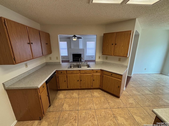 7835 Ruby Mdw, San Antonio, TX 78251 - kitchen featuring a sink, dishwasher, a fireplace, light countertops, and brown cabinets