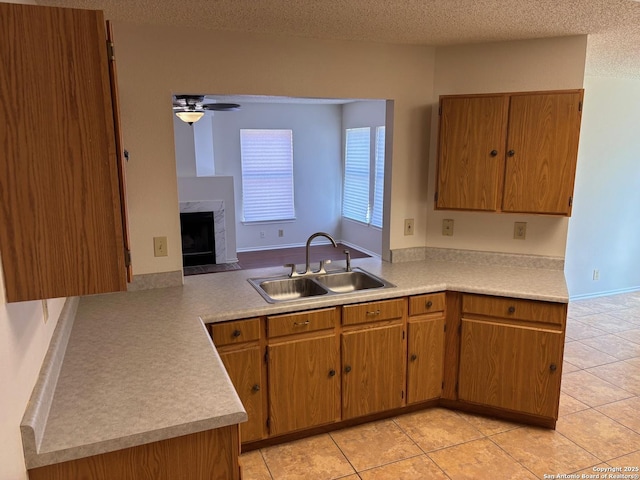 7835 Ruby Mdw, San Antonio, TX 78251 - kitchen featuring a sink, light countertops, a premium fireplace, ceiling fan, and light tile patterned floors