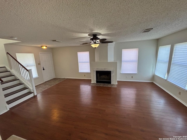 7835 Ruby Mdw, San Antonio, TX 78251 - unfurnished living room with dark wood-style floors, stairs, a ceiling fan, plenty of natural light, and a textured ceiling