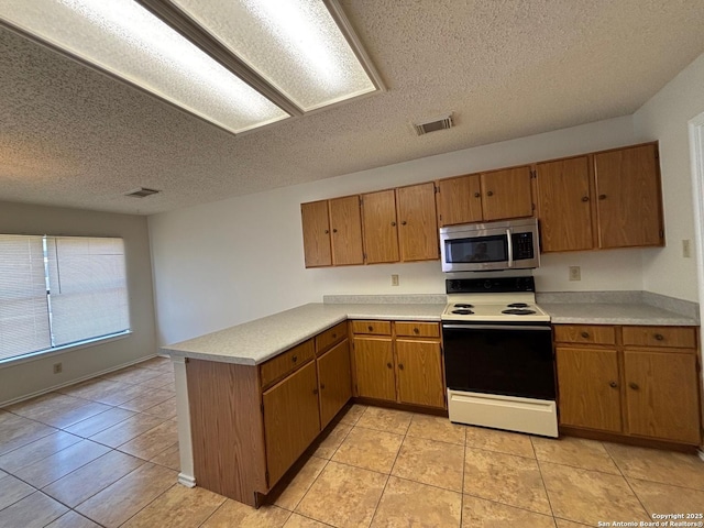 7835 Ruby Mdw, San Antonio, TX 78251 - kitchen with stainless steel microwave, white electric range, a peninsula, light countertops, and a textured ceiling