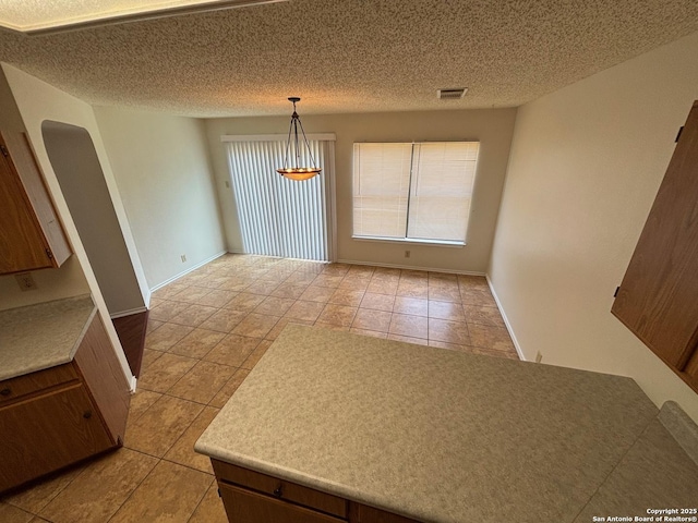 7835 Ruby Mdw, San Antonio, TX 78251 - unfurnished dining area featuring plenty of natural light, light tile patterned floors, arched walkways, and a textured ceiling
