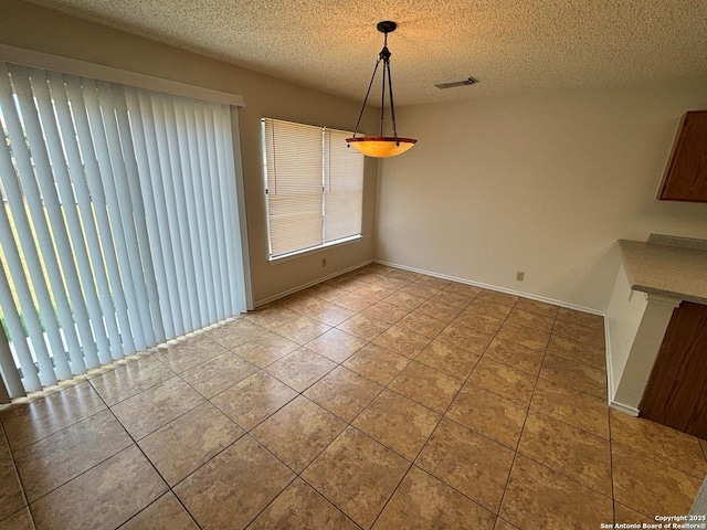 7835 Ruby Mdw, San Antonio, TX 78251 - unfurnished dining area featuring tile patterned flooring, a textured ceiling, and baseboards
