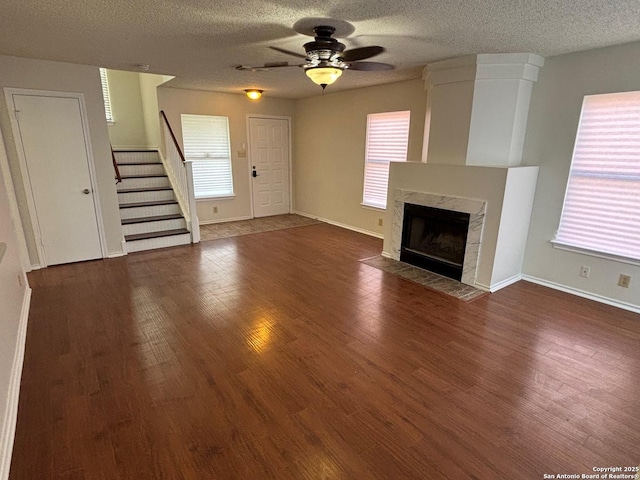 7835 Ruby Mdw, San Antonio, TX 78251 - unfurnished living room with ceiling fan, wood finished floors, a fireplace, stairs, and a textured ceiling