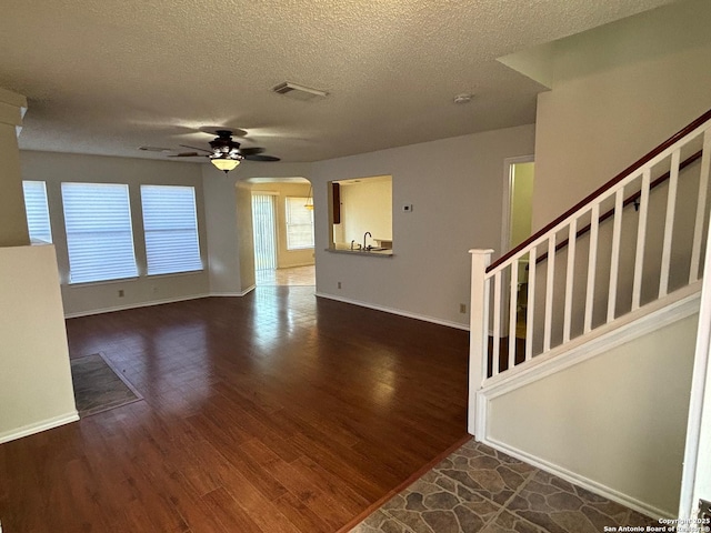 7835 Ruby Mdw, San Antonio, TX 78251 - unfurnished living room with ceiling fan, a textured ceiling, baseboards, arched walkways, and wood finished floors