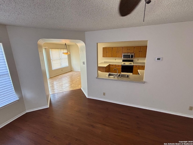 7835 Ruby Mdw, San Antonio, TX 78251 - empty room with arched walkways, a sink, wood finished floors, a ceiling fan, and baseboards