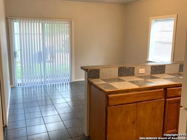 2313 Fresno, San Antonio, TX 78201 - kitchen featuring brown cabinetry, crown molding, dark tile patterned floors, and baseboards