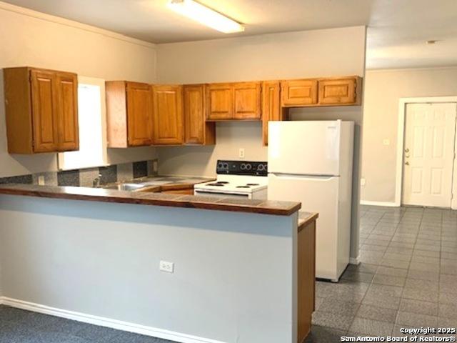 2313 Fresno, San Antonio, TX 78201 - kitchen with white appliances, a peninsula, crown molding, brown cabinets, and baseboards