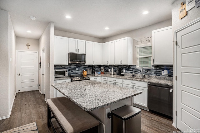 7129 Pisces, Converse, TX 78109 - kitchen featuring appliances with stainless steel finishes, a sink, a breakfast bar area, tasteful backsplash, and white cabinetry