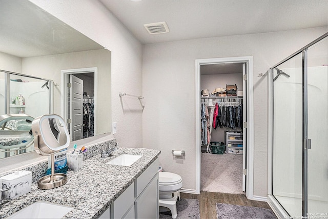 7129 Pisces, Converse, TX 78109 - bathroom featuring a walk in closet, wood finished floors, a shower stall, double vanity, and toilet