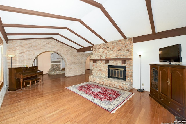 5803 Hollyhock, San Antonio, TX 78240 - living room featuring arched walkways, brick wall, wood finished floors, and a stone fireplace