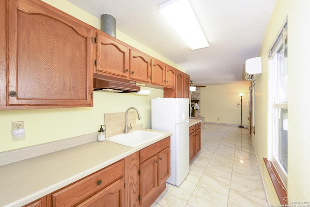 5803 Hollyhock, San Antonio, TX 78240 - kitchen with under cabinet range hood, freestanding refrigerator, a sink, light marble finish flooring, and light countertops