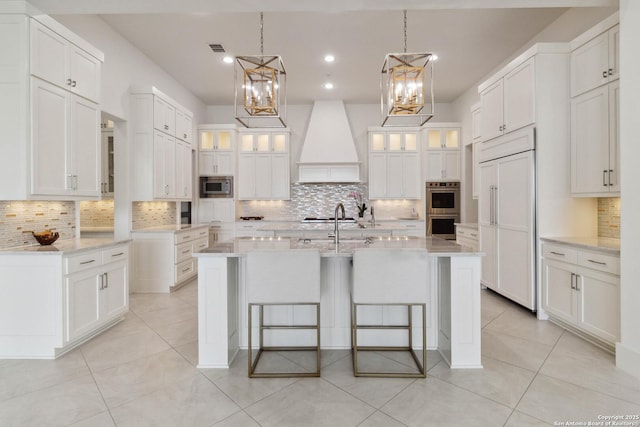 23510 Avila, San Antonio, TX 78255 - kitchen featuring built in appliances, custom range hood, tasteful backsplash, a kitchen island with sink, and a breakfast bar area