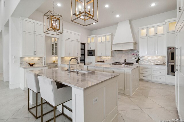23510 Avila, San Antonio, TX 78255 - kitchen with a large island with sink, premium range hood, stainless steel appliances, a sink, and a chandelier