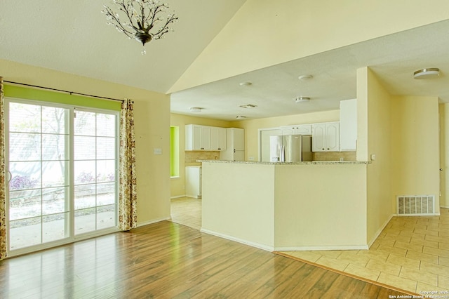 15018 Miss Ellie Dr, San Antonio, TX 78247 - kitchen with stainless steel refrigerator with ice dispenser, white cabinetry, lofted ceiling, a peninsula, and light wood-type flooring