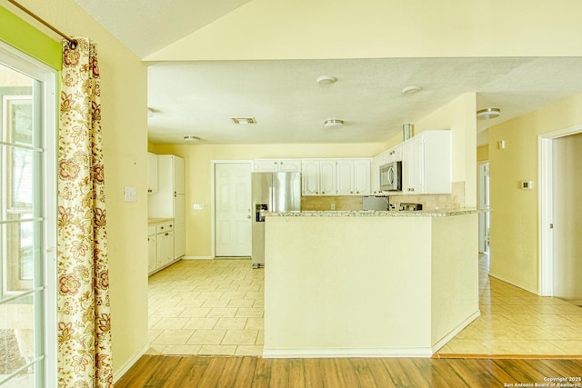 15018 Miss Ellie Dr, San Antonio, TX 78247 - kitchen featuring appliances with stainless steel finishes, light tile patterned flooring, white cabinetry, a peninsula, and vaulted ceiling