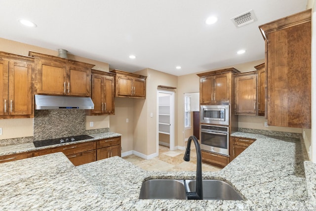 22919 Hightop, Elmendorf, TX 78112 - kitchen featuring stainless steel appliances, exhaust hood, a sink, brown cabinets, and recessed lighting