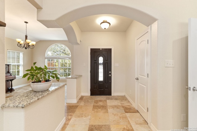 22919 Hightop, Elmendorf, TX 78112 - entryway with arched walkways, a chandelier, baseboards, and light stone finish flooring