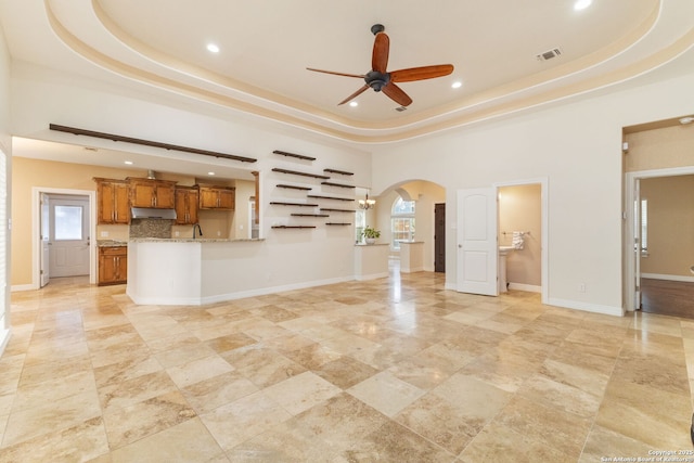 22919 Hightop, Elmendorf, TX 78112 - unfurnished living room featuring a raised ceiling, a ceiling fan, arched walkways, recessed lighting, and healthy amount of natural light
