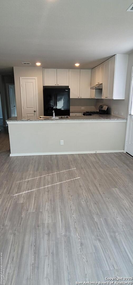 10814 Prusiner, Converse, TX 78109 - kitchen featuring range, black refrigerator with ice dispenser, under cabinet range hood, wood finished floors, and a sink
