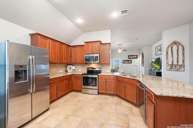 1926 Kalli Jo Ln, New Braunfels, TX 78130 - kitchen with appliances with stainless steel finishes, a sink, a peninsula, brown cabinets, and vaulted ceiling