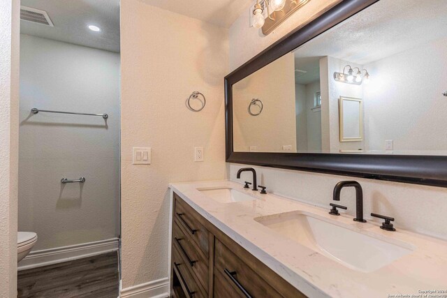 1309 Quintana Rd, San Antonio, TX 78211 - full bath featuring toilet, double vanity, wood finished floors, baseboards, and recessed lighting