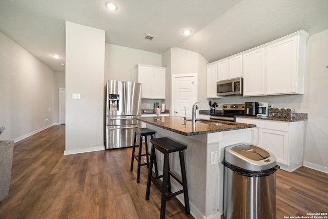 6907 Emerald Vly, San Antonio, TX 78242 - kitchen featuring appliances with stainless steel finishes, baseboards, a kitchen bar, dark wood-type flooring, and a center island with sink