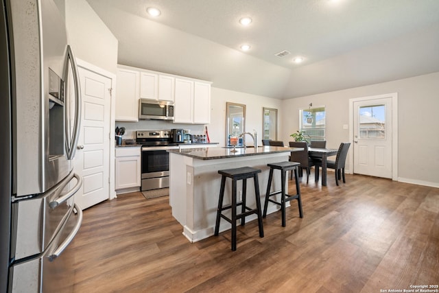 6907 Emerald Vly, San Antonio, TX 78242 - kitchen with appliances with stainless steel finishes, a kitchen bar, vaulted ceiling, dark wood-type flooring, and a kitchen island with sink