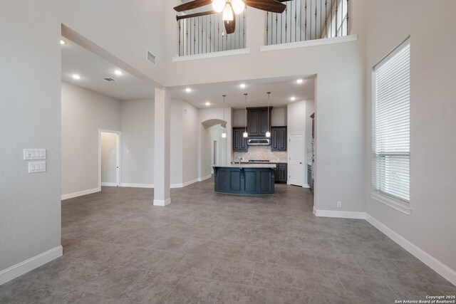 25448 River Ledge, San Antonio, TX 78255 - unfurnished living room featuring a ceiling fan, arched walkways, a high ceiling, baseboards, and recessed lighting
