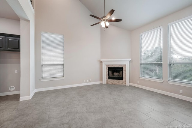 25448 River Ledge, San Antonio, TX 78255 - unfurnished living room featuring a ceiling fan, a tiled fireplace, baseboards, tile patterned floors, and high vaulted ceiling