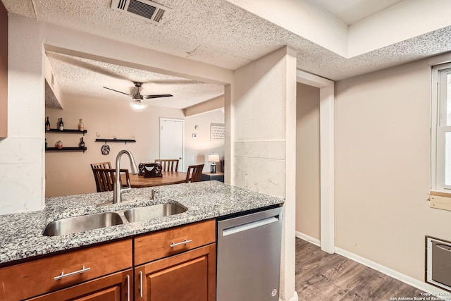 8517 Echo Crk, San Antonio, TX 78240 - kitchen with stainless steel dishwasher, a sink, brown cabinetry, a textured ceiling, and light wood finished floors