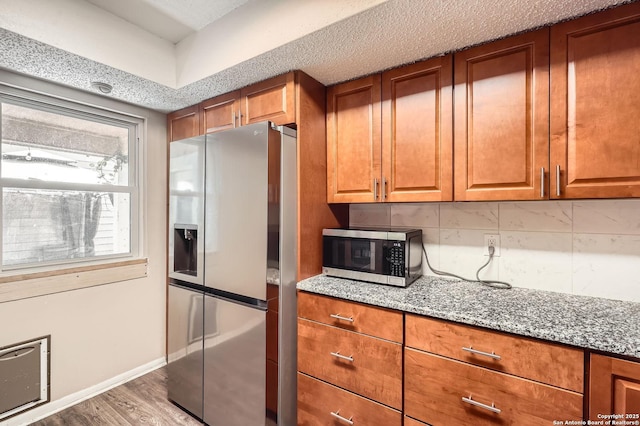 8517 Echo Crk, San Antonio, TX 78240 - kitchen featuring stainless steel appliances, brown cabinetry, light stone countertops, and tasteful backsplash