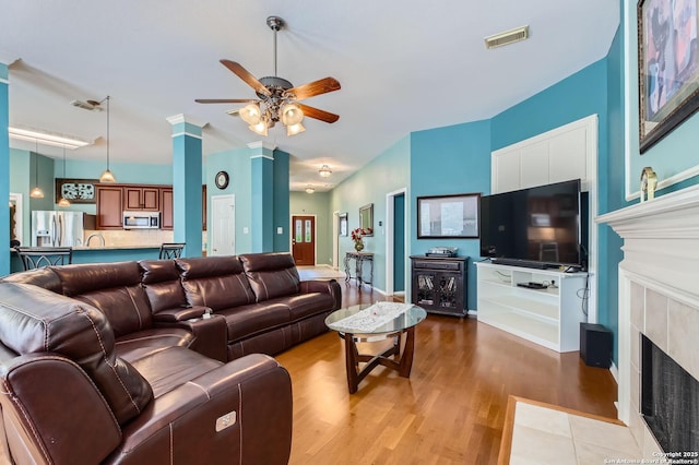 1730 Escada, San Antonio, TX 78258 - living room with a tile fireplace, a ceiling fan, and light wood-type flooring