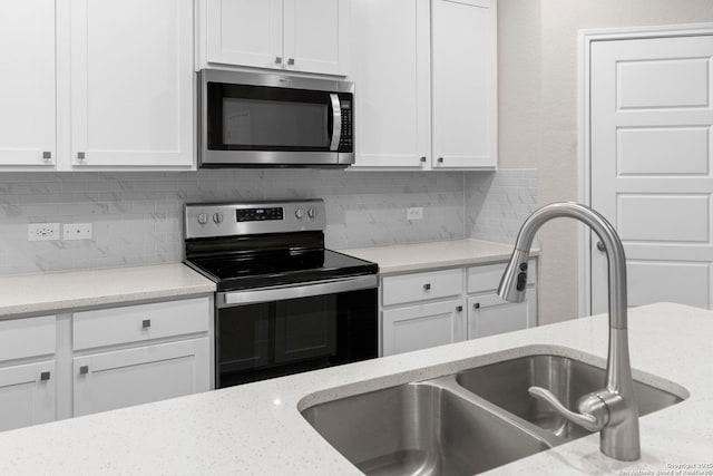 3065 Charyn Way, New Braunfels, TX 78132 - kitchen with appliances with stainless steel finishes, a sink, white cabinets, tasteful backsplash, and light stone counters