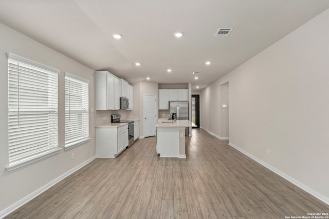 3065 Charyn Way, New Braunfels, TX 78132 - kitchen featuring appliances with stainless steel finishes, light wood-style flooring, light countertops, recessed lighting, and white cabinetry