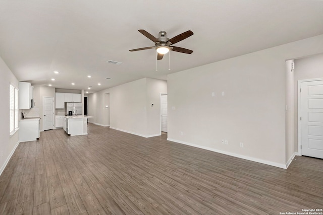3065 Charyn Way, New Braunfels, TX 78132 - unfurnished living room with ceiling fan, wood finished floors, baseboards, recessed lighting, and a sink