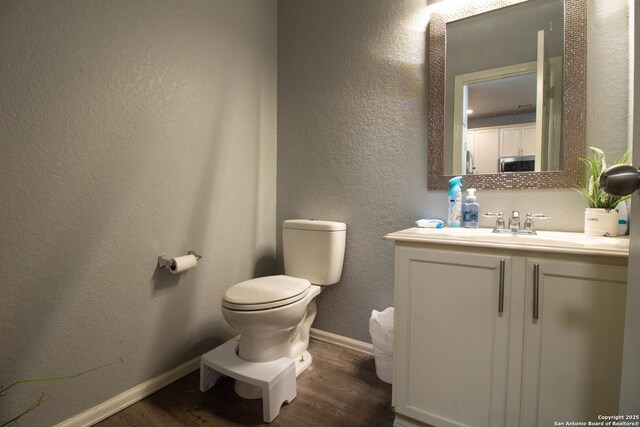 2547 Grayson, San Antonio, TX 78232 - bathroom featuring wood finished floors, toilet, vanity, baseboards, and a textured wall
