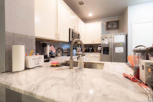 2547 Grayson, San Antonio, TX 78232 - kitchen featuring stainless steel appliances, light stone countertops, white cabinets, and tasteful backsplash