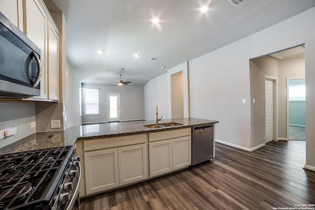 11741 Troubadour Trl, San Antonio, TX 78245 - kitchen featuring appliances with stainless steel finishes, a sink, dark wood-style floors, dark stone counters, and a peninsula