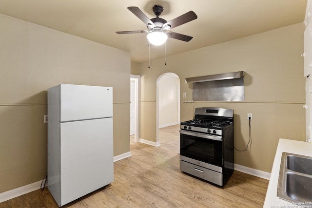 1001 Mason, San Antonio, TX 78208 - kitchen featuring freestanding refrigerator, stainless steel gas stove, arched walkways, ceiling fan, and light wood finished floors