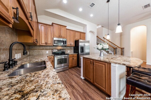 1210 Magellan, Windcrest, TX 78239 - kitchen with appliances with stainless steel finishes, a sink, arched walkways, a kitchen island, and dark wood-type flooring