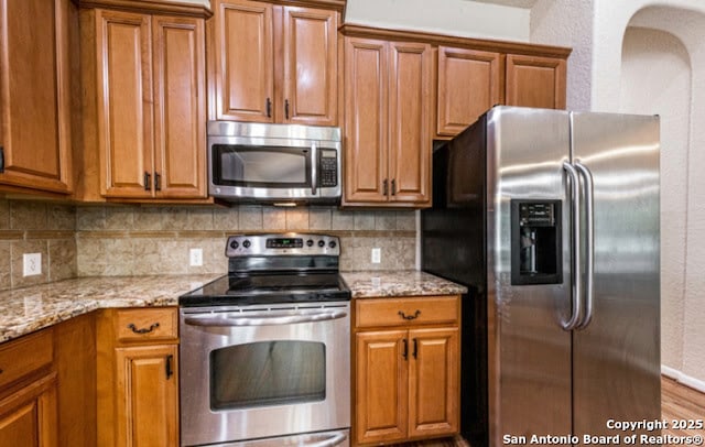 1210 Magellan, Windcrest, TX 78239 - kitchen with stainless steel appliances, brown cabinetry, tasteful backsplash, and light stone counters