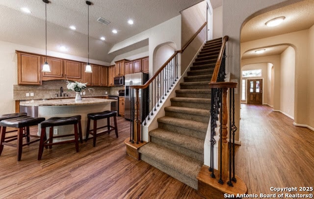 1210 Magellan, Windcrest, TX 78239 - kitchen with wood finished floors, appliances with stainless steel finishes, arched walkways, a center island, and a textured ceiling