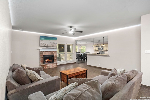 4222 Manitou Bay, San Antonio, TX 78259 - living room with ceiling fan, dark wood-style flooring, a brick fireplace, and baseboards