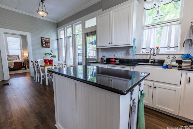 225 W Humphreys, Seguin, TX 78155 - kitchen with dark countertops, a sink, ornamental molding, white cabinetry, and dark wood finished floors