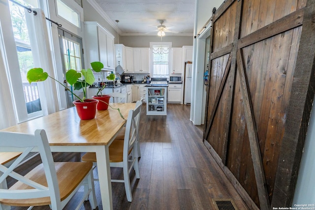 225 W Humphreys, Seguin, TX 78155 - dining space featuring a barn door, ornamental molding, dark wood finished floors, and ceiling fan