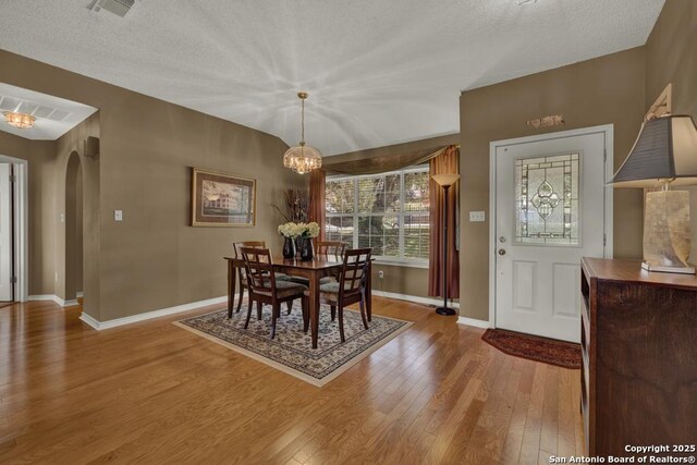 821 Lakeview, Canyon Lake, TX 78133 - dining area with arched walkways, a chandelier, wood finished floors, baseboards, and a textured ceiling
