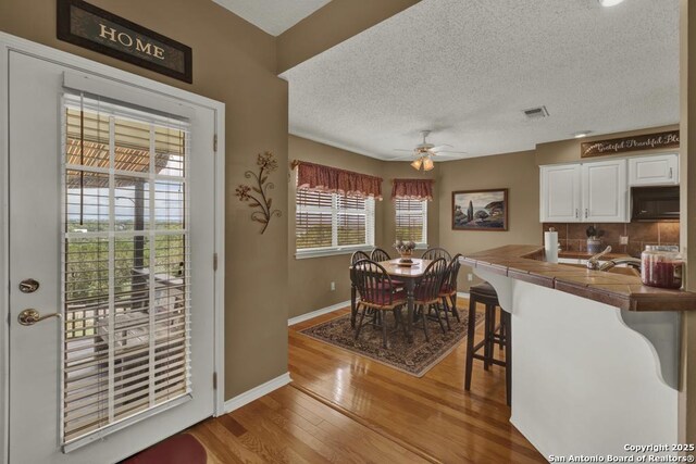 821 Lakeview, Canyon Lake, TX 78133 - dining area featuring light wood-style flooring, baseboards, ceiling fan, and a textured ceiling